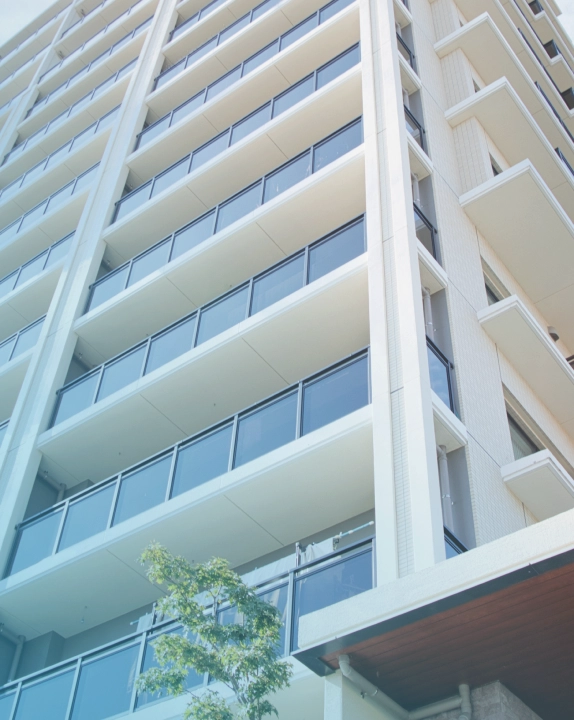 ガラス張りの白いマンションの外観写真 - アセットコンサルティング事業の不動産投資を表現